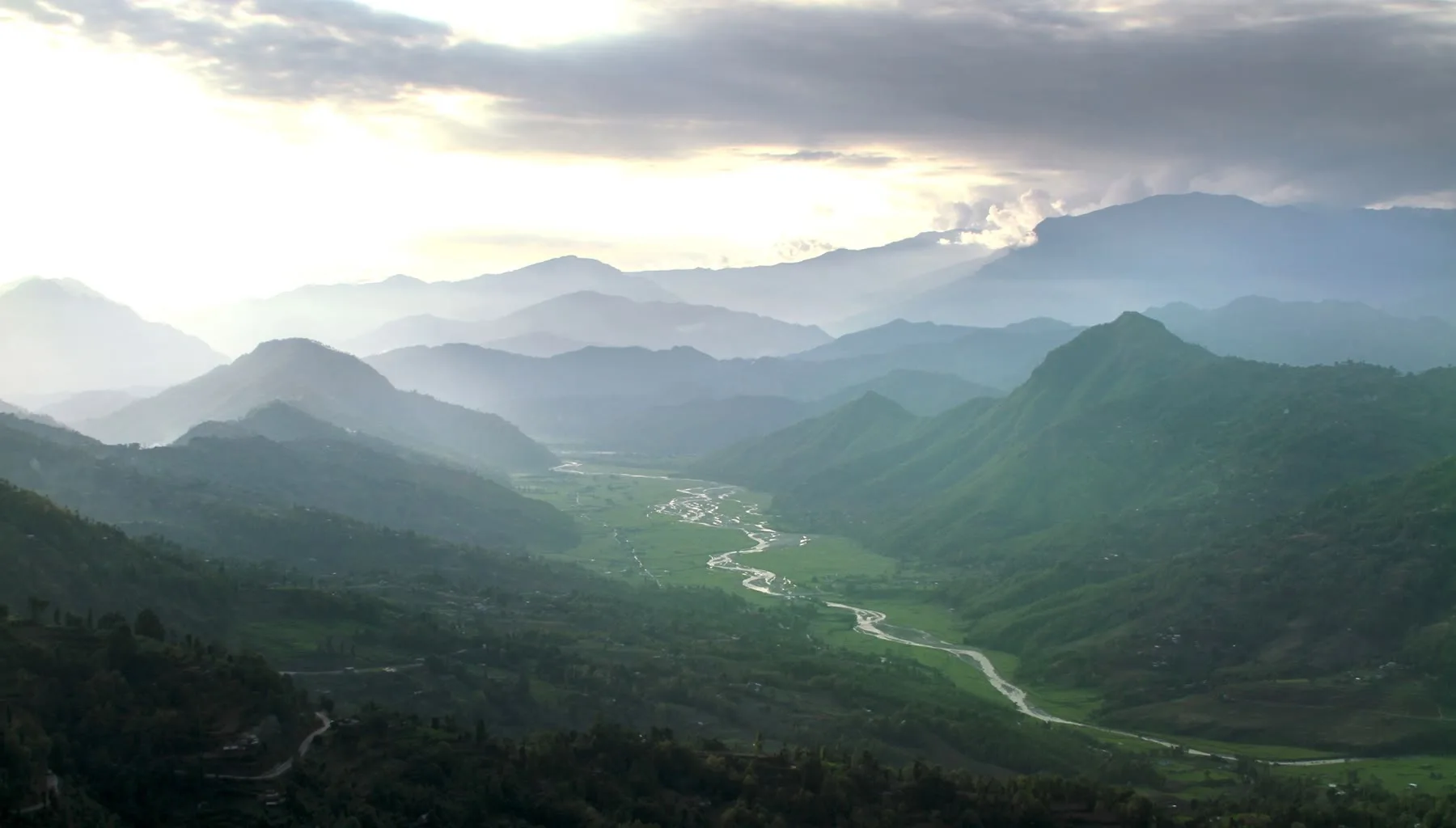 A river winding through a wide valley under layered hills