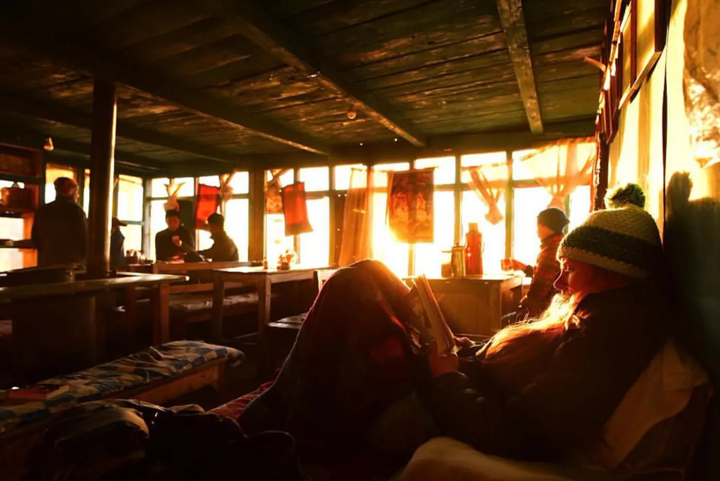 Trekkers resting by the window of a wooden mountain homestay